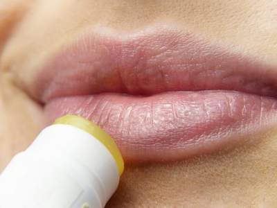 A woman is applying a Lip Balm with SPF on her lips