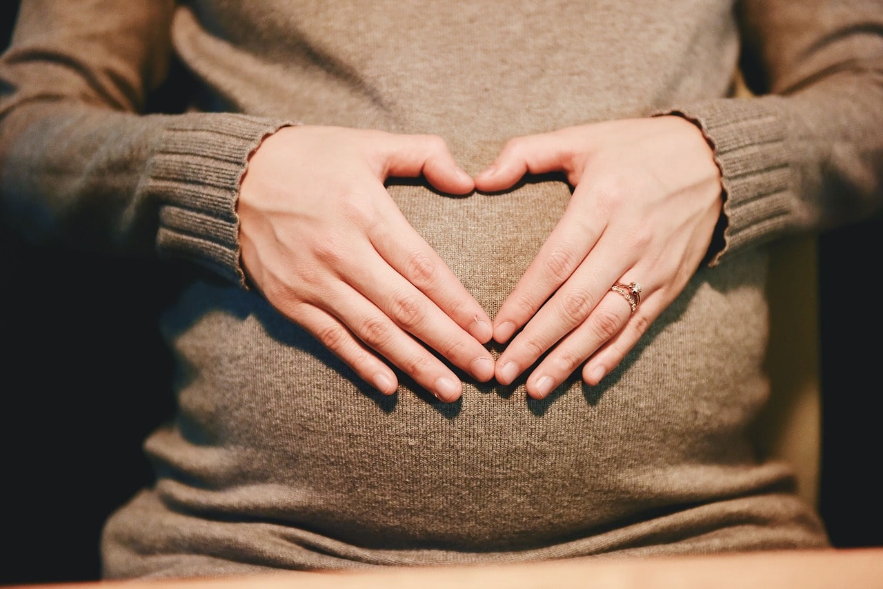 pregnant woman shaping heart with her hands