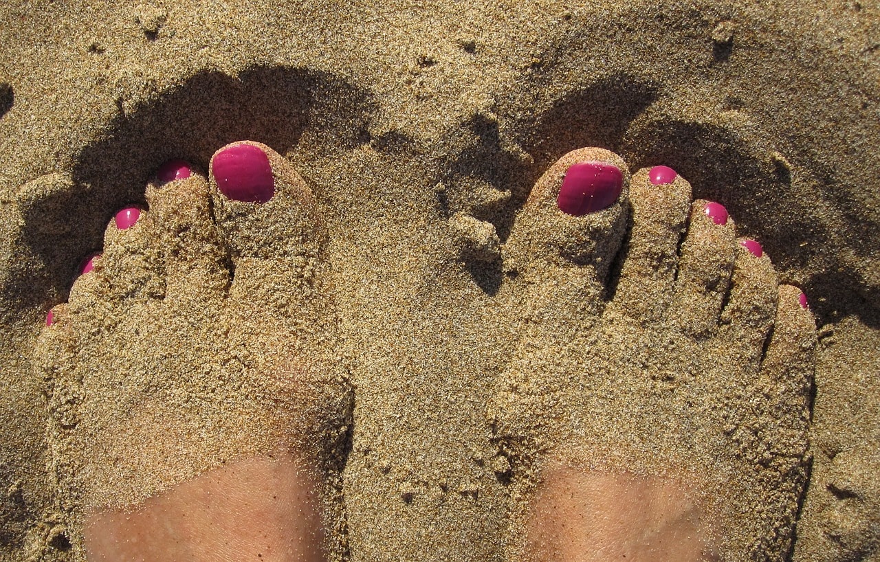 women's legs in a sand on the beach
