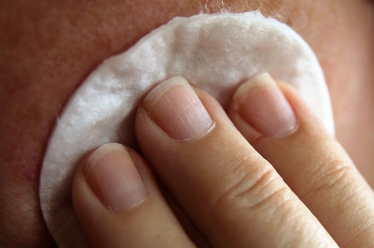 applying a cleanser gently with a cotton pad