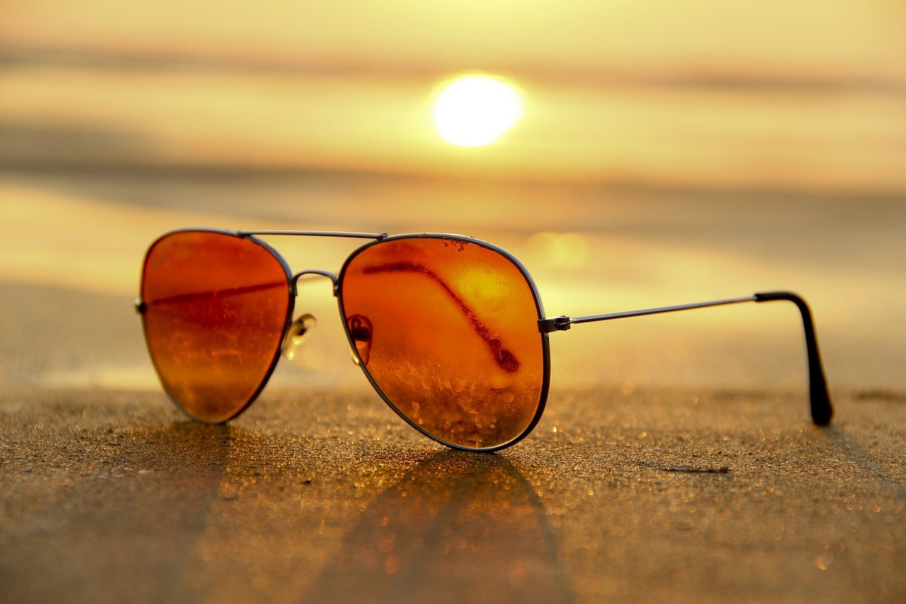 sunglasses on the beach and the sunset behind